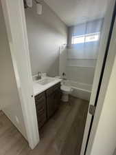 Full bathroom with toilet, vanity, tub / shower combination, and wood finished floors