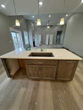 Kitchen with open floor plan, light countertops, a sink, and light wood finished floors