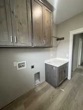 Clothes washing area with washer hookup, cabinet space, wood finished floors, and hookup for an electric dryer