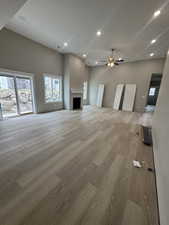 Unfurnished living room with a fireplace, a ceiling fan, light wood finished floors, and recessed lighting