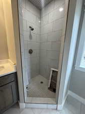Bathroom featuring marble finish floor, vanity, a stall shower, and baseboards
