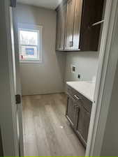 Washroom featuring hookup for a washing machine, light wood-style floors, cabinet space, and electric dryer hookup