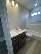 Bathroom featuring tub / shower combination, vanity, toilet, and wood finished floors