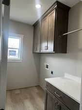 Clothes washing area featuring washer hookup, cabinet space, light wood-style floors, and electric dryer hookup