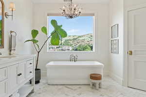 Bathroom with vanity, a chandelier, visible vents, baseboards, and a freestanding bath
