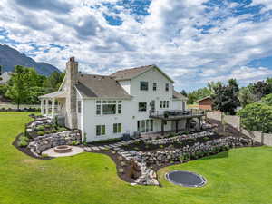 Rear view of property with a fire pit, a chimney, and a lawn