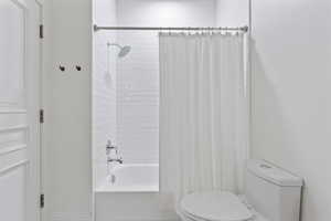 Full bathroom with toilet and shower / bath combo with shower curtain
