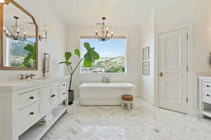 Bathroom featuring baseboards, a freestanding bath, vanity, and an inviting chandelier