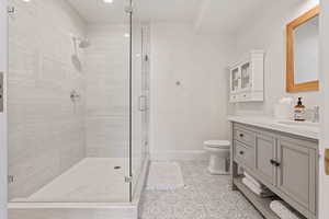 Full bathroom with baseboards, toilet, vanity, a stall shower, and tile patterned flooring