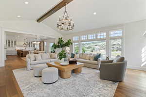 Living room featuring baseboards, beam ceiling, hardwood / wood-style flooring, and a chandelier