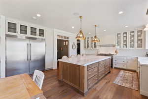 Kitchen with a center island, white cabinets, dark wood finished floors, and premium appliances