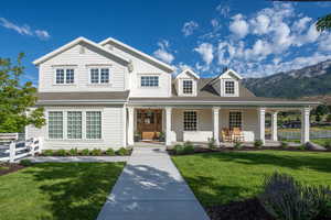 View of front facade featuring a shingled roof, fence, a front lawn, and a porch