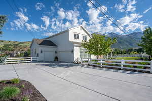 View of home's exterior featuring an attached garage, a mountain view, concrete driveway, and fence