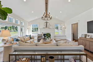 Living room featuring lofted ceiling with beams, wood finished floors, baseboards, recessed lighting, and an inviting chandelier