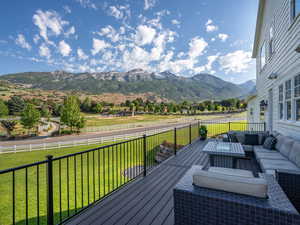 Wooden terrace with an outdoor hangout area, fence, a rural view, a lawn, and a mountain view