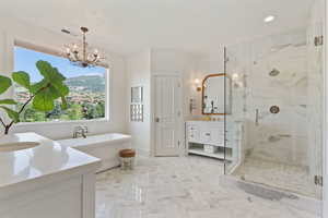 Full bath featuring visible vents, vanity, a stall shower, a freestanding bath, and a notable chandelier
