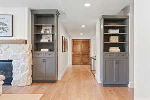 Corridor featuring light wood finished floors, baseboards, built in features, and recessed lighting