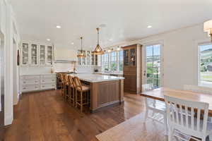 Kitchen with a kitchen island, dark wood-type flooring, premium range hood, and double oven range