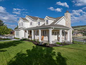 View of front of property featuring a chimney, a front lawn, a porch, and roof with shingles