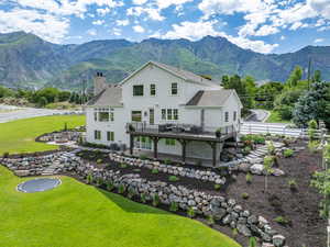 Back of house with a chimney, fence, a patio, a deck with mountain view, and a lawn