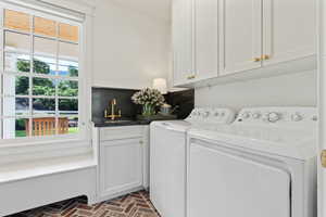 Laundry area with brick floor, washing machine and clothes dryer, cabinet space, and a sink