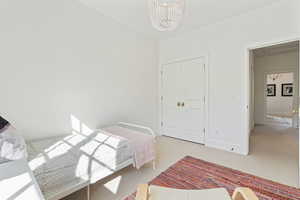 Bedroom featuring baseboards, a closet, a notable chandelier, and light colored carpet