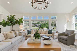 Living area featuring vaulted ceiling, light wood-style flooring, recessed lighting, and a chandelier