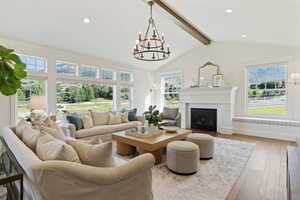 Living room with a glass covered fireplace, recessed lighting, a chandelier, hardwood / wood-style flooring, and vaulted ceiling with beams