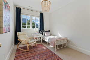 Carpeted bedroom with a notable chandelier, baseboards, and visible vents