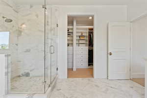 Bathroom with a spacious closet, baseboards, and a shower stall