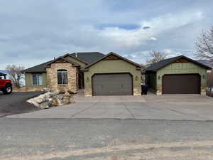 Craftsman inspired home featuring stone siding, an attached & detached garage, a shingled roof, and concrete driveway