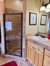 Full bath featuring a stall shower, separate tub, and vanity