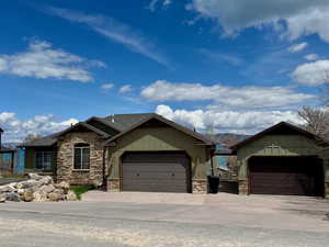 View of front of home with a garage, board and batten siding, concrete driveway, and stone siding