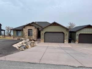 Craftsman inspired home featuring driveway, an attached garage, stone siding, and roof with shingles