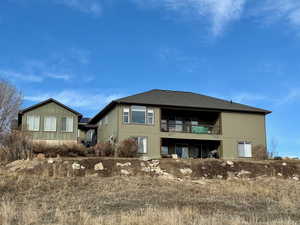 Back of house with a balcony and a shingled roof