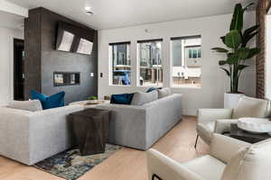 Living area with light wood-type flooring, visible vents, a tiled fireplace, and an accent wall