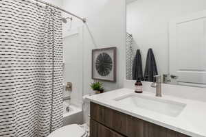 Full bathroom with toilet, vanity, and shower / bathtub combination with curtain