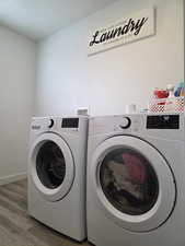 Washroom featuring separate washer and dryer, baseboards, laundry area, and wood finished floors