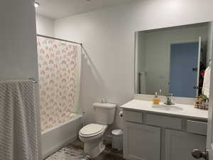 Full bath featuring toilet, vanity, shower / bath combo, and wood finished floors