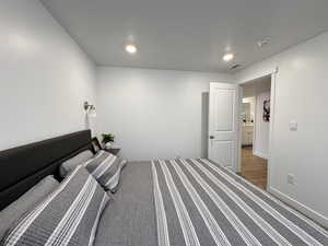Bedroom with baseboards, visible vents, and wood finished floors