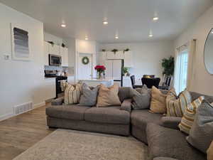 Living room featuring baseboards, visible vents, wood finished floors, and recessed lighting
