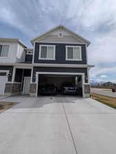 View of front of property with driveway, stone siding, and a garage