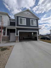 View of front of property with stone siding, concrete driveway, and an attached garage