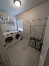 Washroom with baseboards, a textured ceiling, laundry area, and washer and dryer