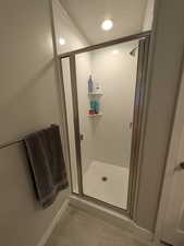 Full bathroom with a shower stall, baseboards, recessed lighting, and a textured ceiling