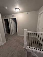 Hall with baseboards, carpet flooring, and visible vents