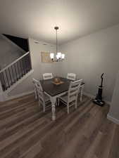 Dining space featuring stairs, a notable chandelier, wood finished floors, a textured ceiling, and baseboards
