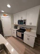 Kitchen featuring light countertops, backsplash, white cabinets, and appliances with stainless steel finishes