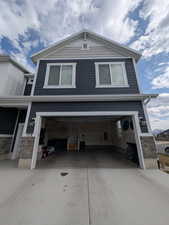 View of property exterior with an attached garage, stone siding, and concrete driveway