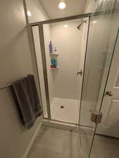 Bathroom featuring a textured ceiling, baseboards, and a shower stall